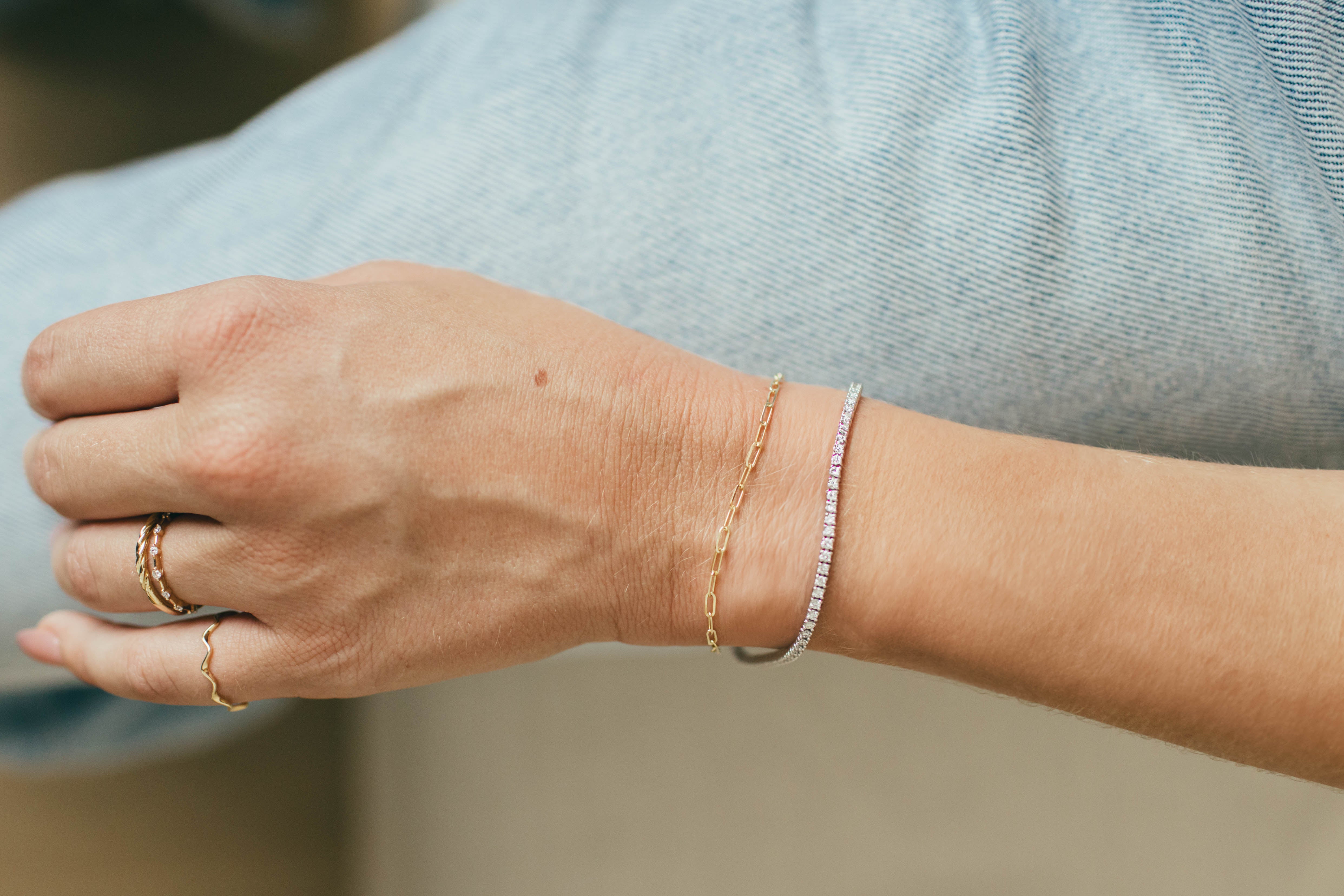 Hand wearing gold rings and bracelets with a blurred background