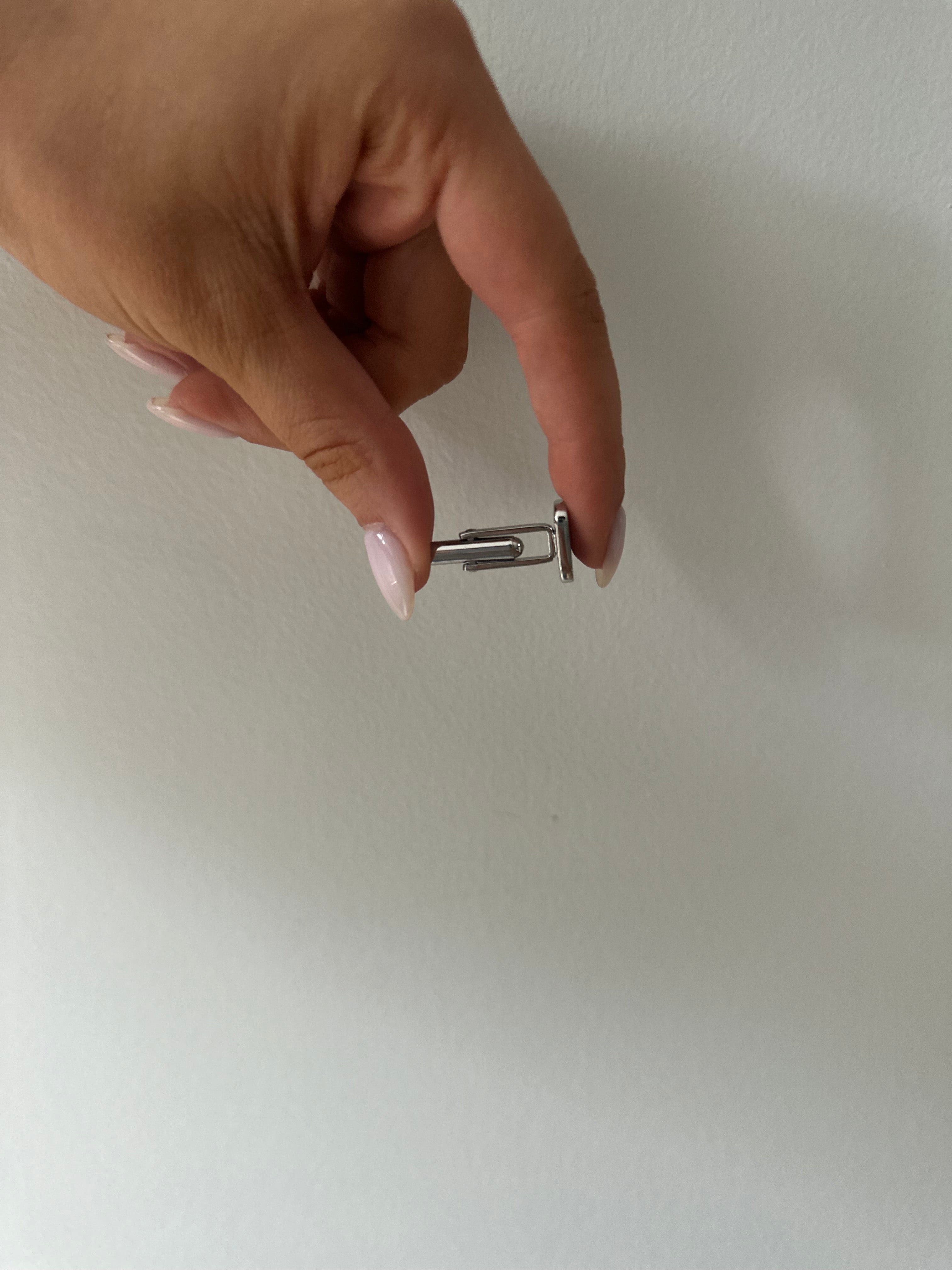 A side profile of a men's square stainless steel cufflink against a neutral background.