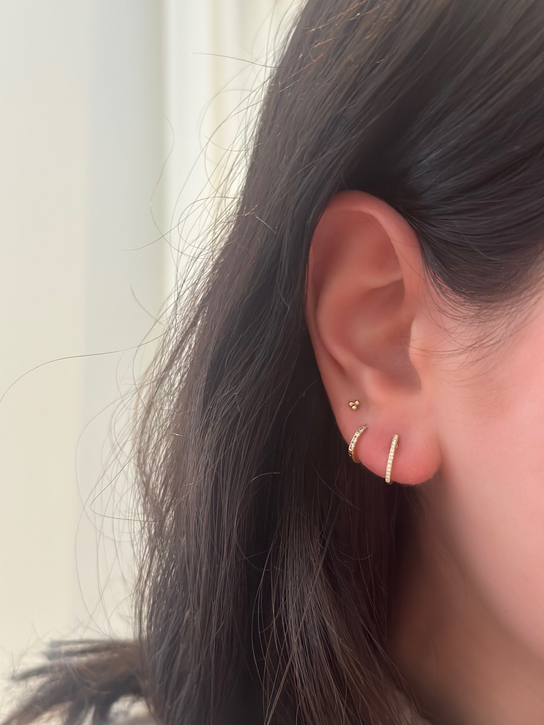 close up of girls ear wearing diamond huggies