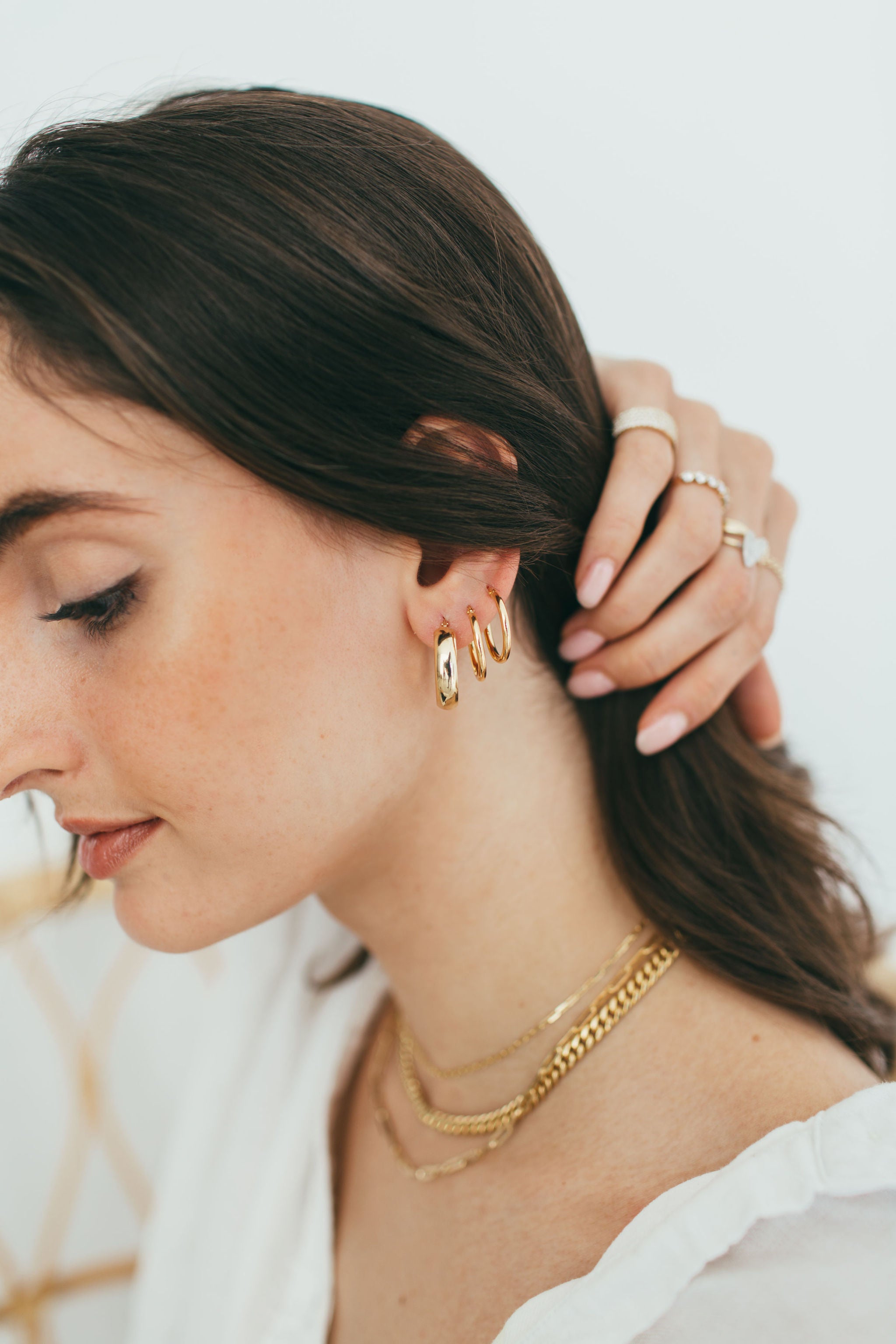 girl pulling her hair back to reveal gold hoop stack 
