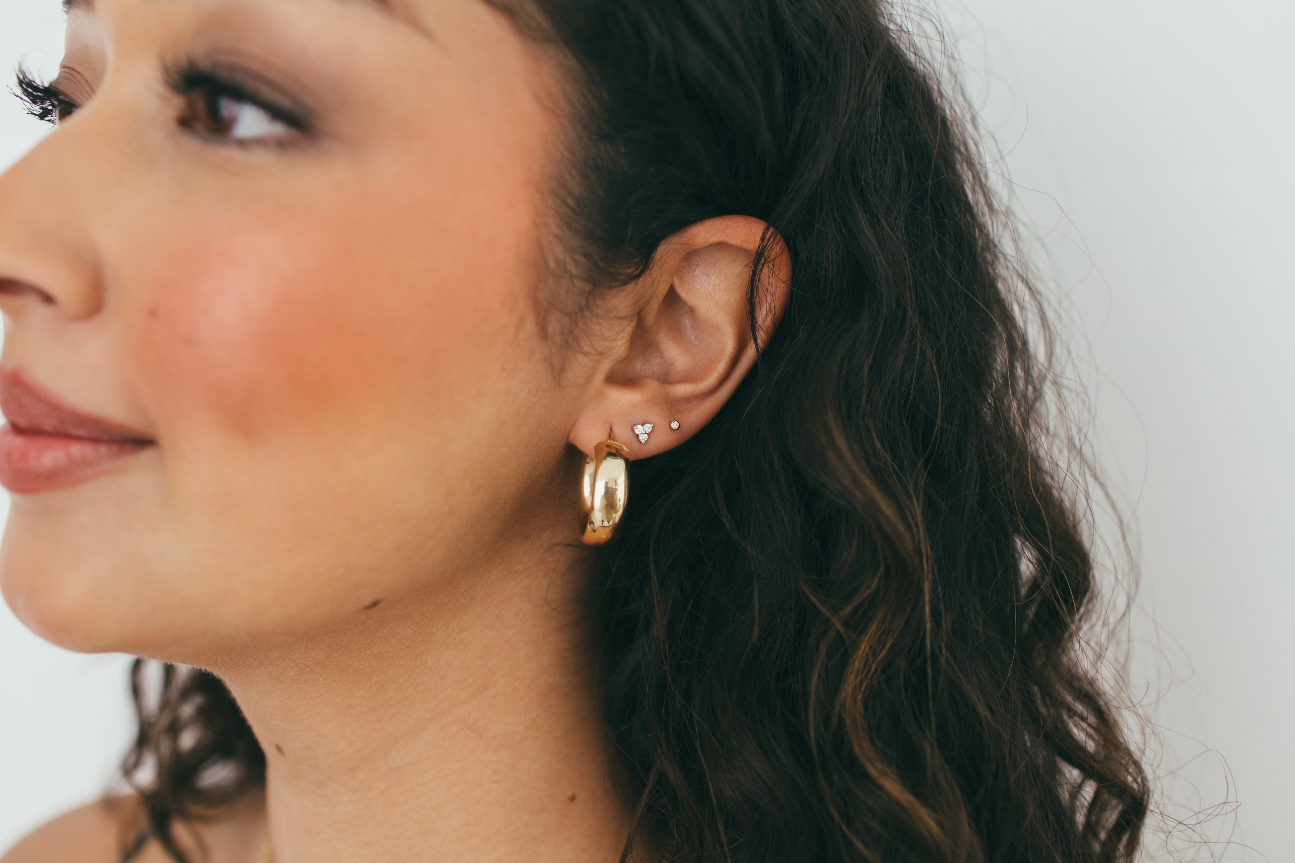 close up of girl wearing chunky gold hoops and diamond studs