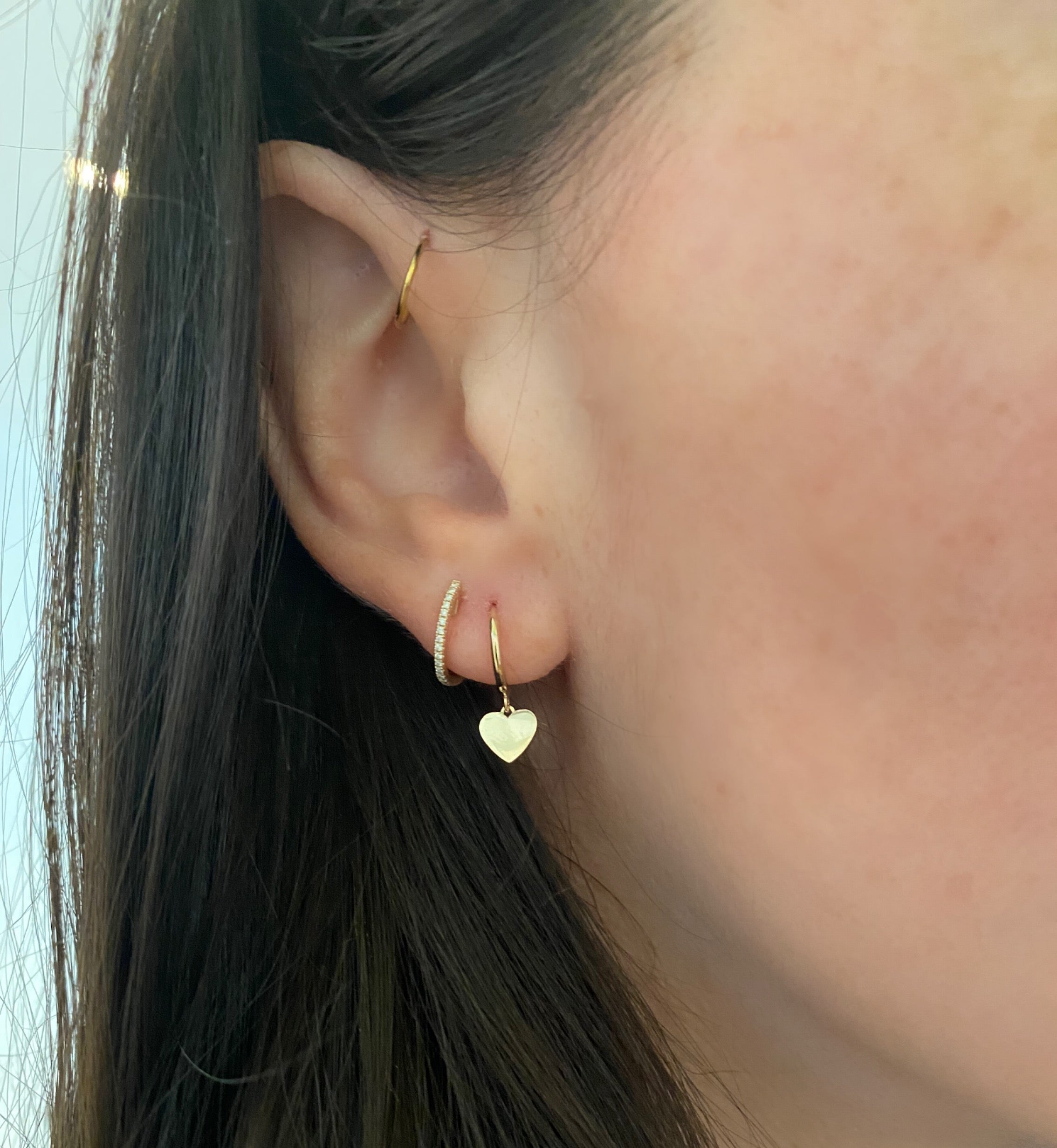 close up of ear wearing dangling heart huggies and diamond huggie