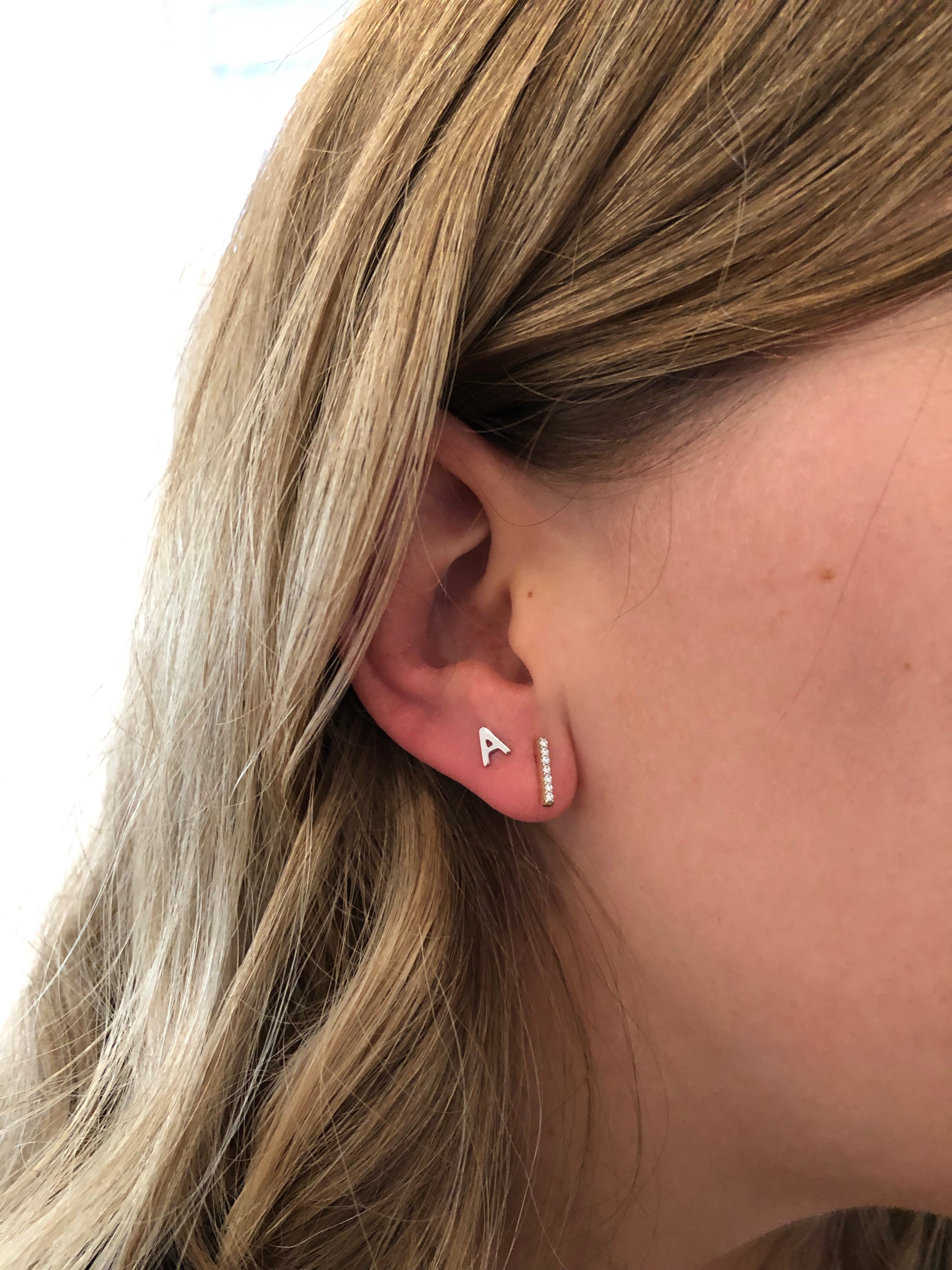 close up of girl wearing an initial A stud and diamond bar stud