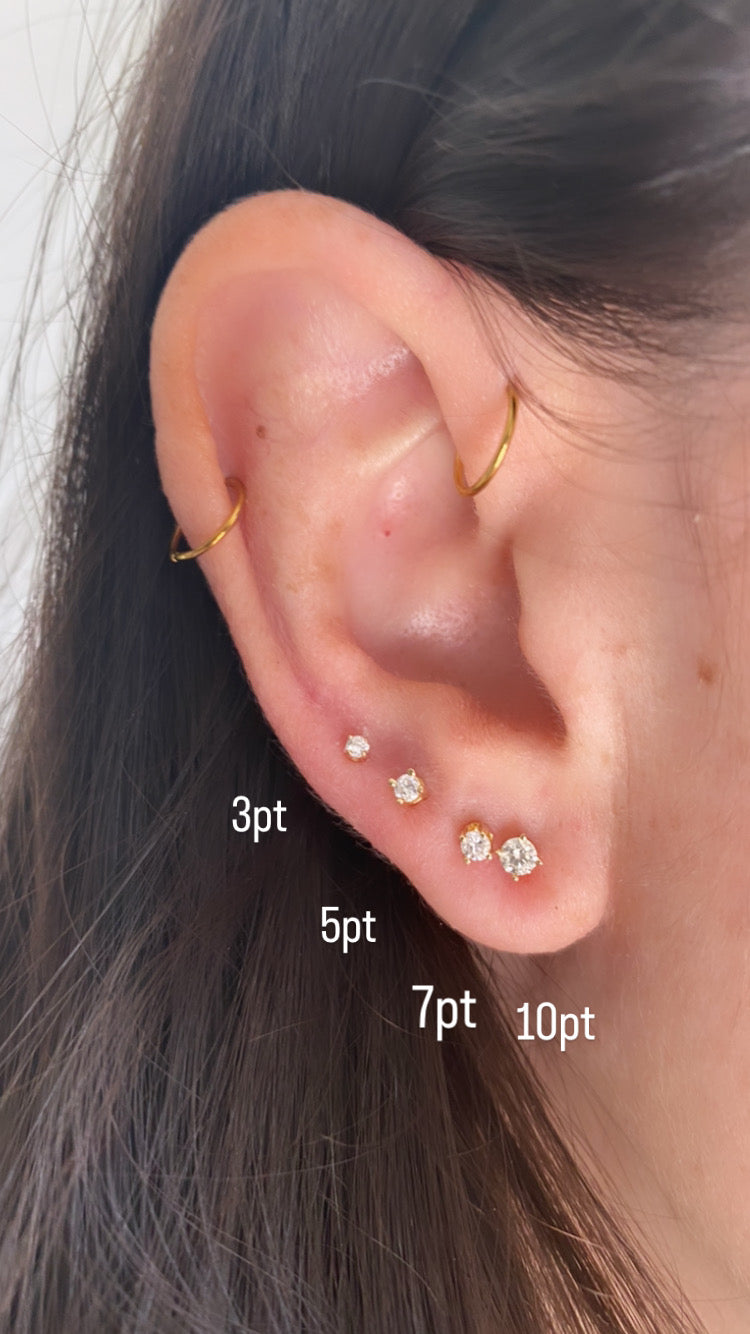 close up of ear wearing all different sizes of diamond studs