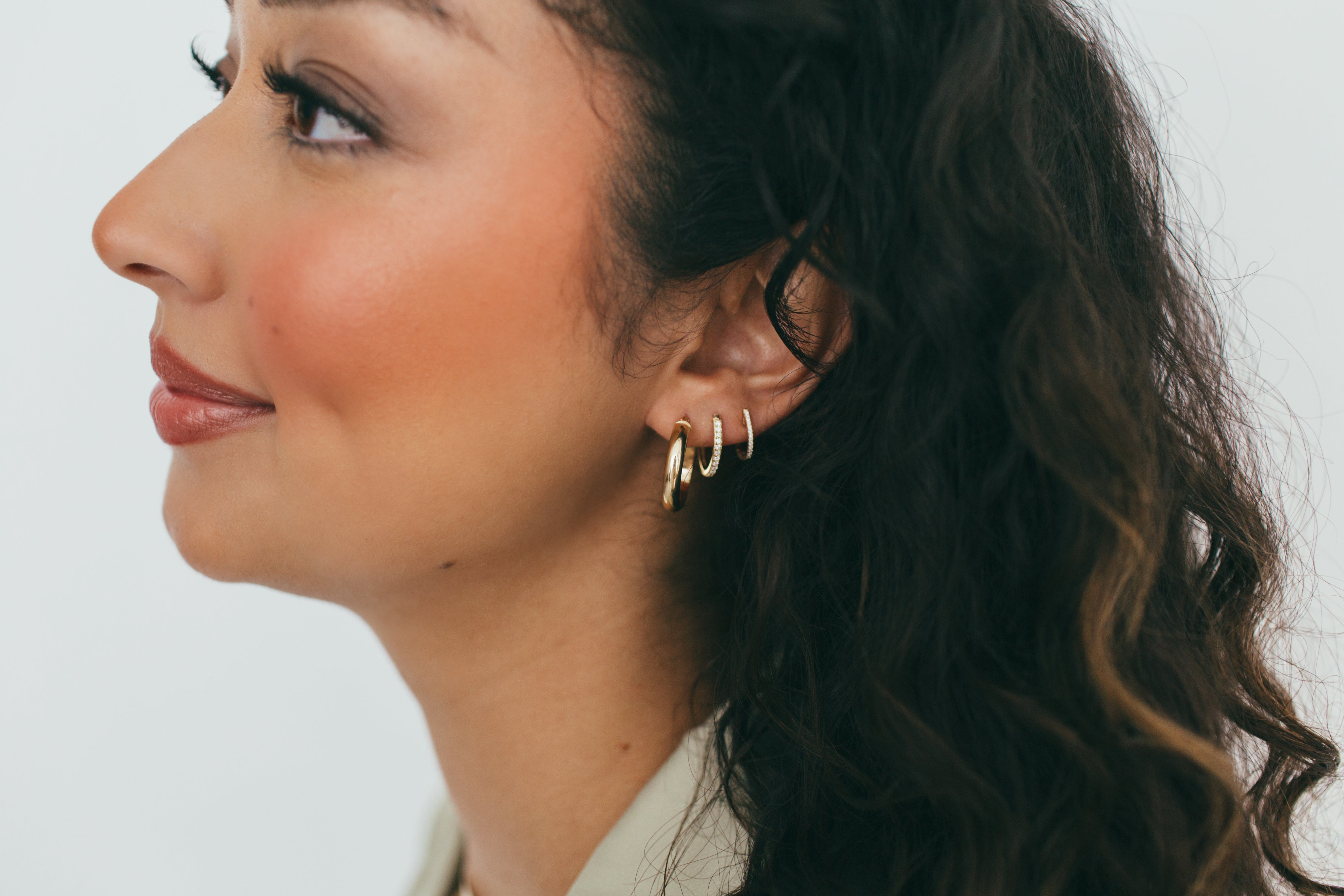 Layered look featuring 14 karat gold diamond hoops paired with minimalist gold hoop earrings, showcasing versatility and style.