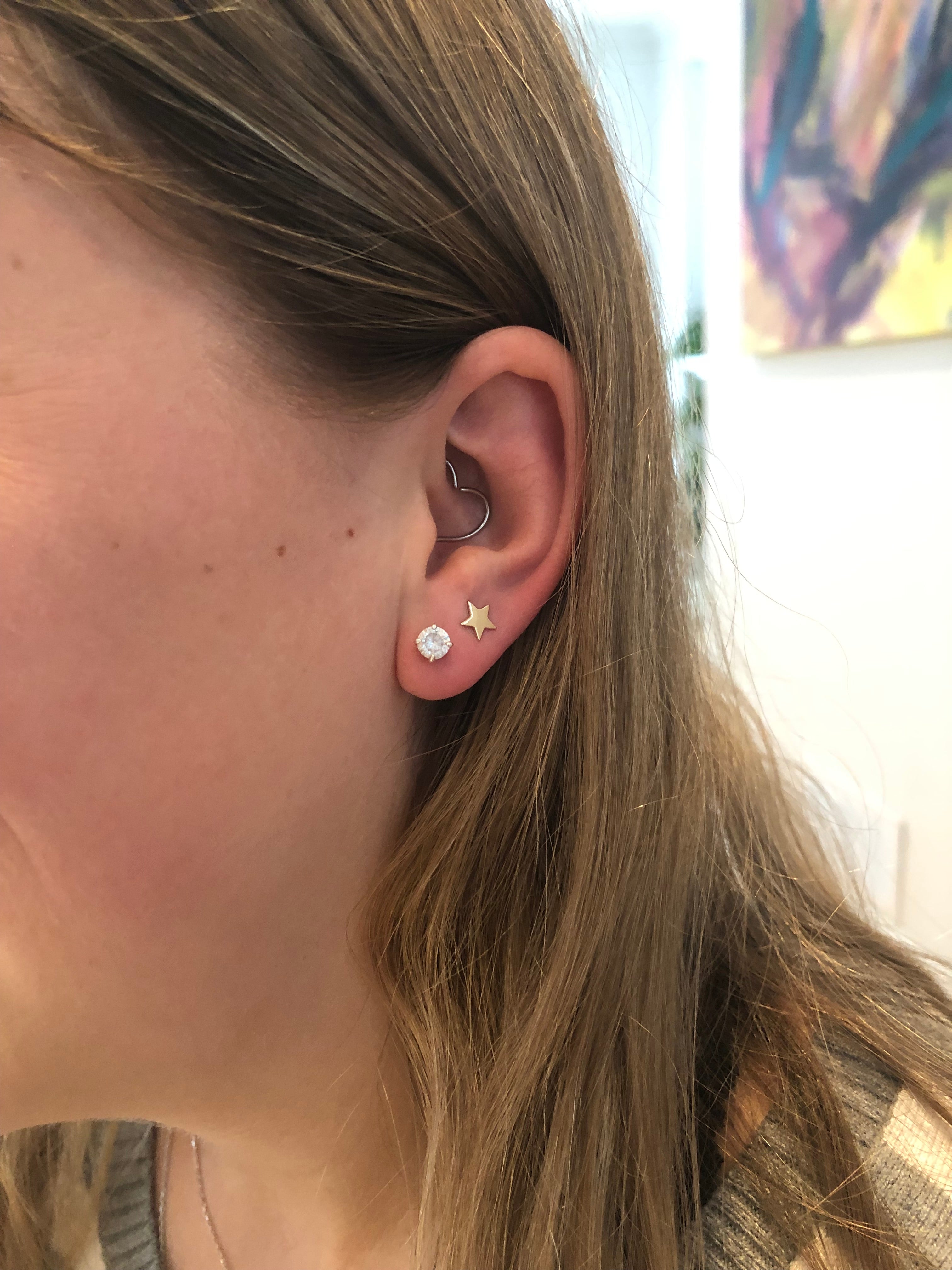 close up of girls ear wearing diamond studs and gold stud earrings