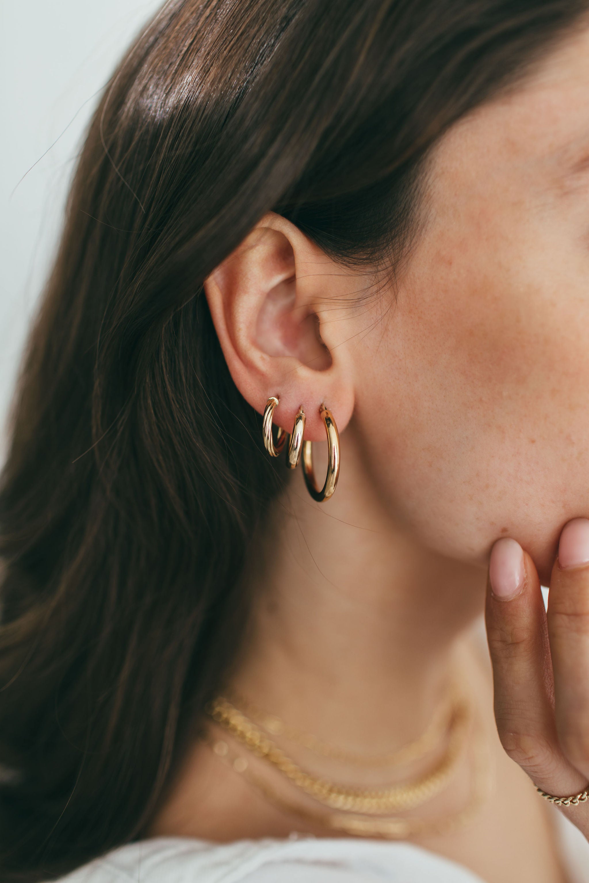 an ear displaying a stack of three gold hoops in multiple sizes