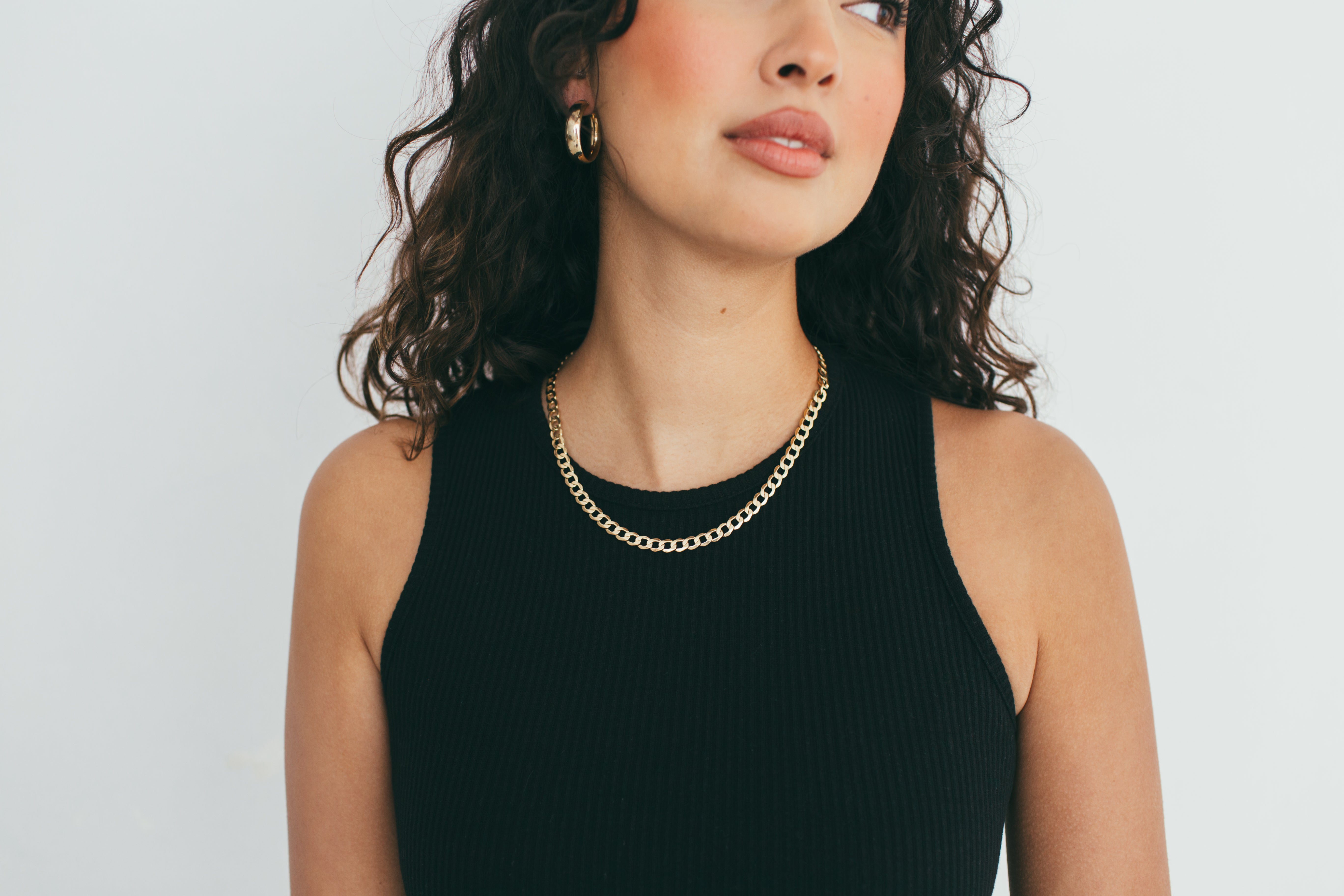 Model wearing 7mm thick gold hoops, showcasing their versatility and statement style.