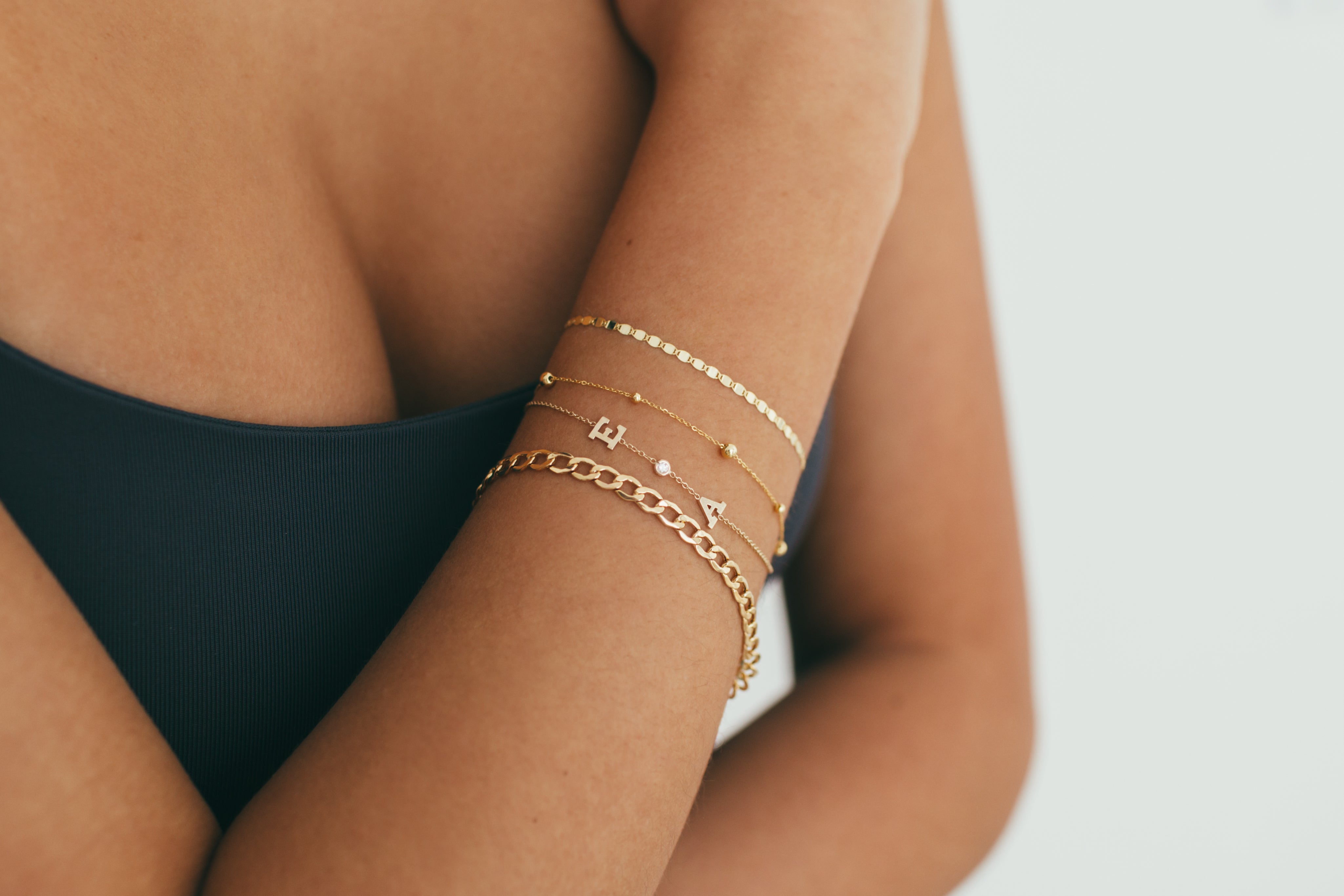 Model displaying Jessica Jewellery's Bold Initial and Diamond Bracelet paired with other fine bracelets, highlighting its customization options and elegant design.