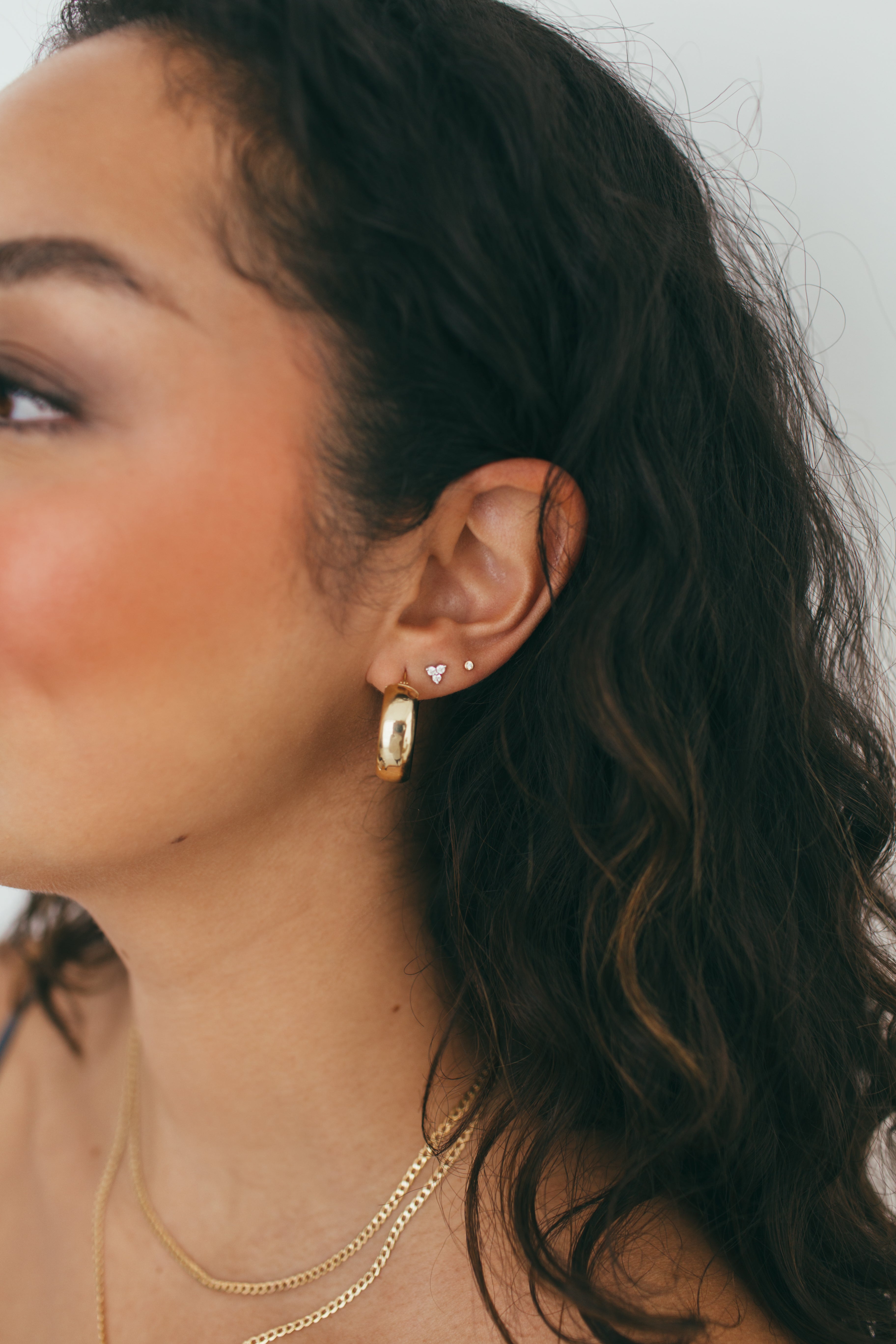 girl wearing chunky gold hoops and diamond studs