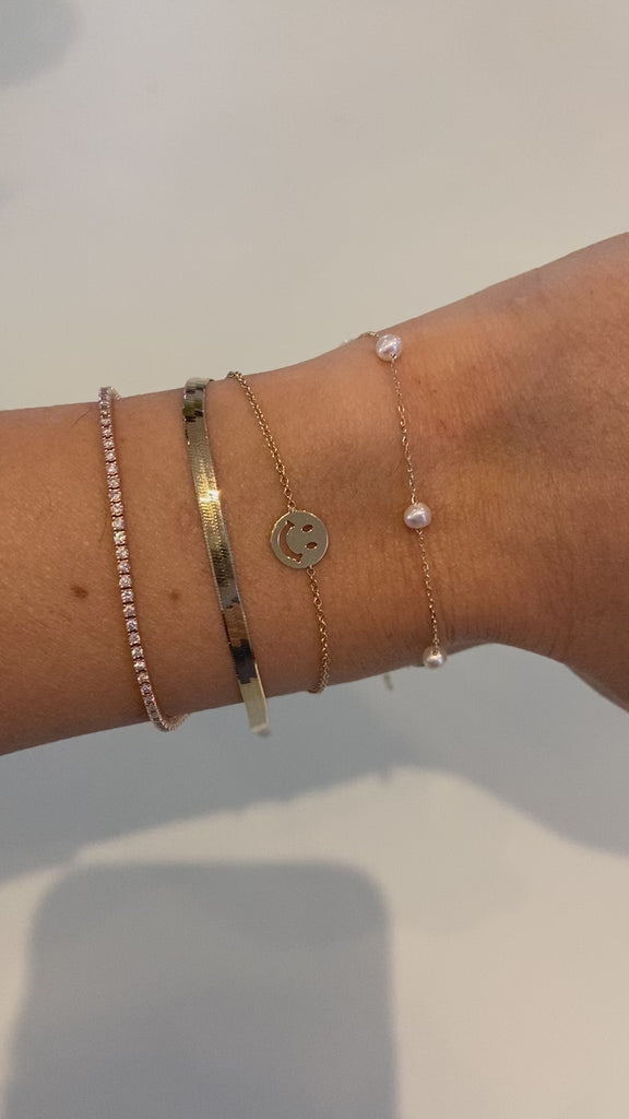 Artistic presentation of the Petite Pearl Bracelet by Jessica Jewellery on a textured surface.