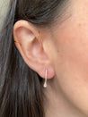 Side view of diamond huggie earrings featuring pear-shaped diamond drop.
