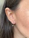Elegant diamond huggie earrings with pear-shaped drop on display.